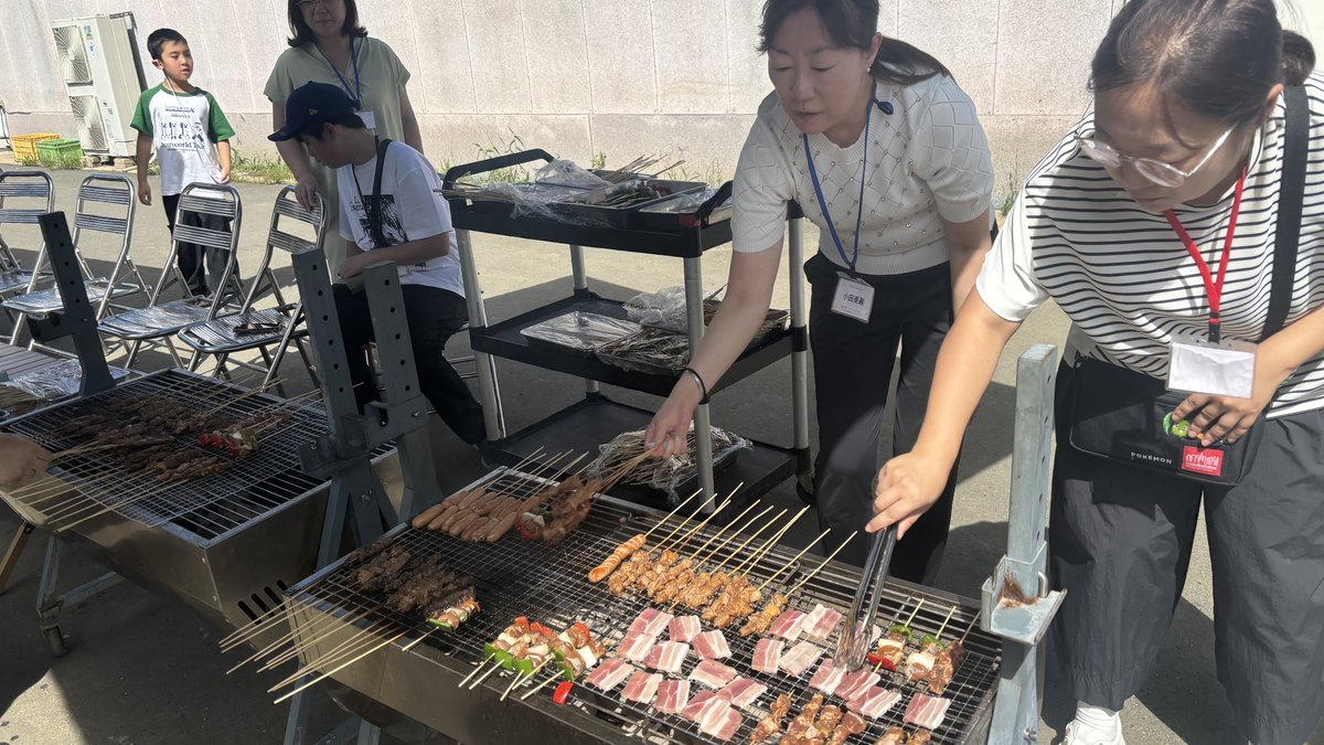 親子でバーベキューの串を焼く参加者