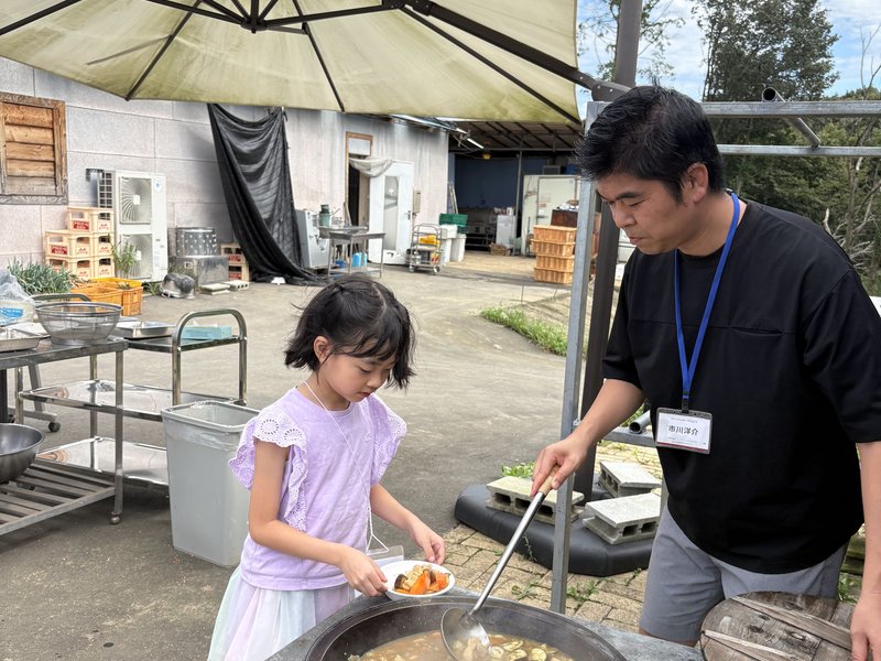 大きな鍋で調理を体験する子ども