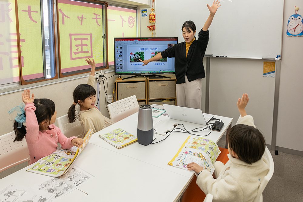 手を挙げて発表する子どもたちと中国語講師