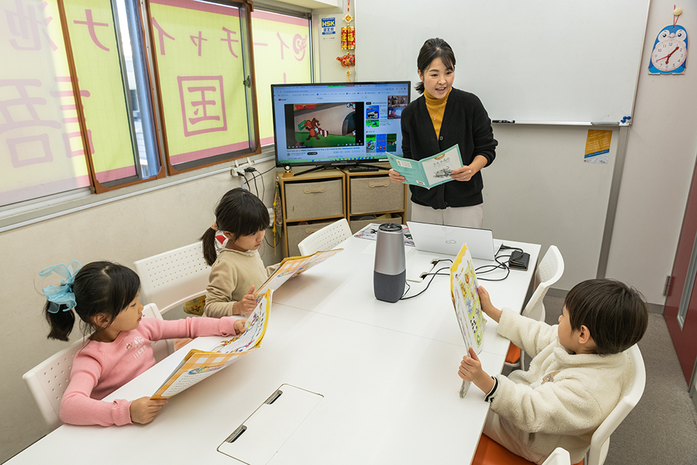 テキストを見せ合う子ども中国語レッスン